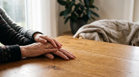 Mains de deux générations posées ensemble sur une table en bois, symbolisant la transmission du patrimoine et la préparation de la retraite grâce à l'assurance vie